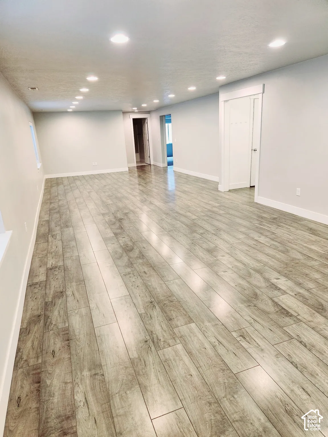 Expansive interior space featuring wood-finish flooring, recessed lighting, and light-toned wall finishes