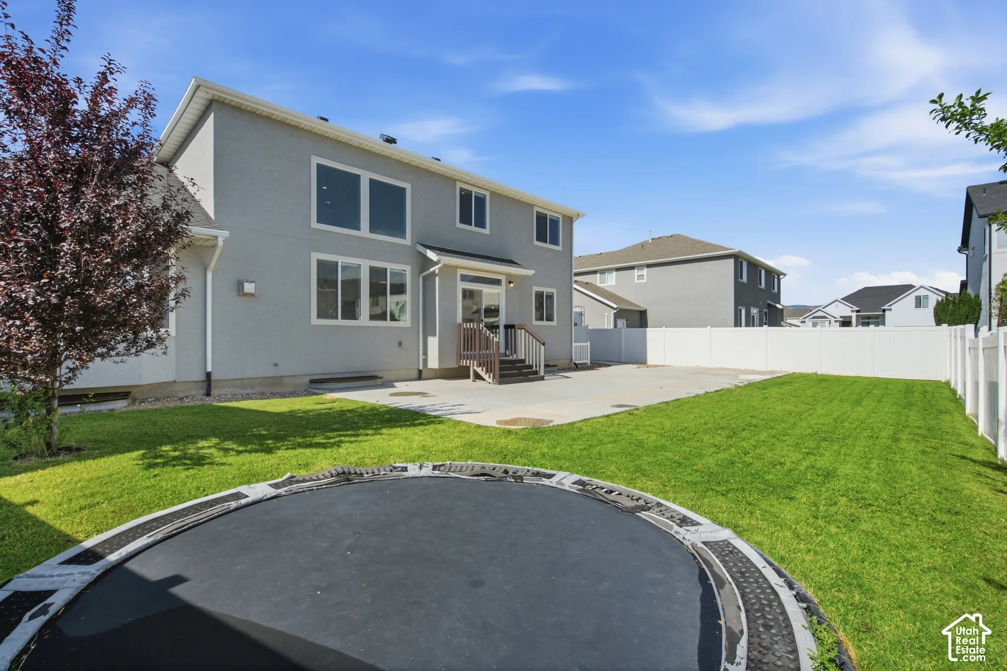Expansive backyard featuring a manicured lawn, a large concrete patio, and a privacy fence