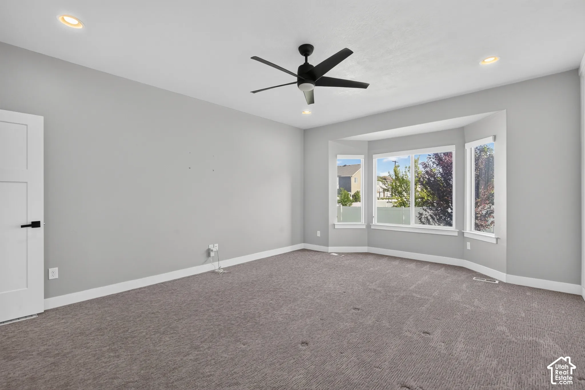 Spacious room featuring a bay window, recessed lighting, and a contemporary ceiling fan