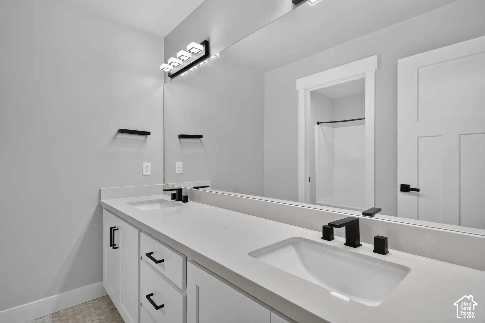 Spacious bathroom featuring a dual vanity with white cabinetry, light-toned countertops, and integrated rectangular sinks