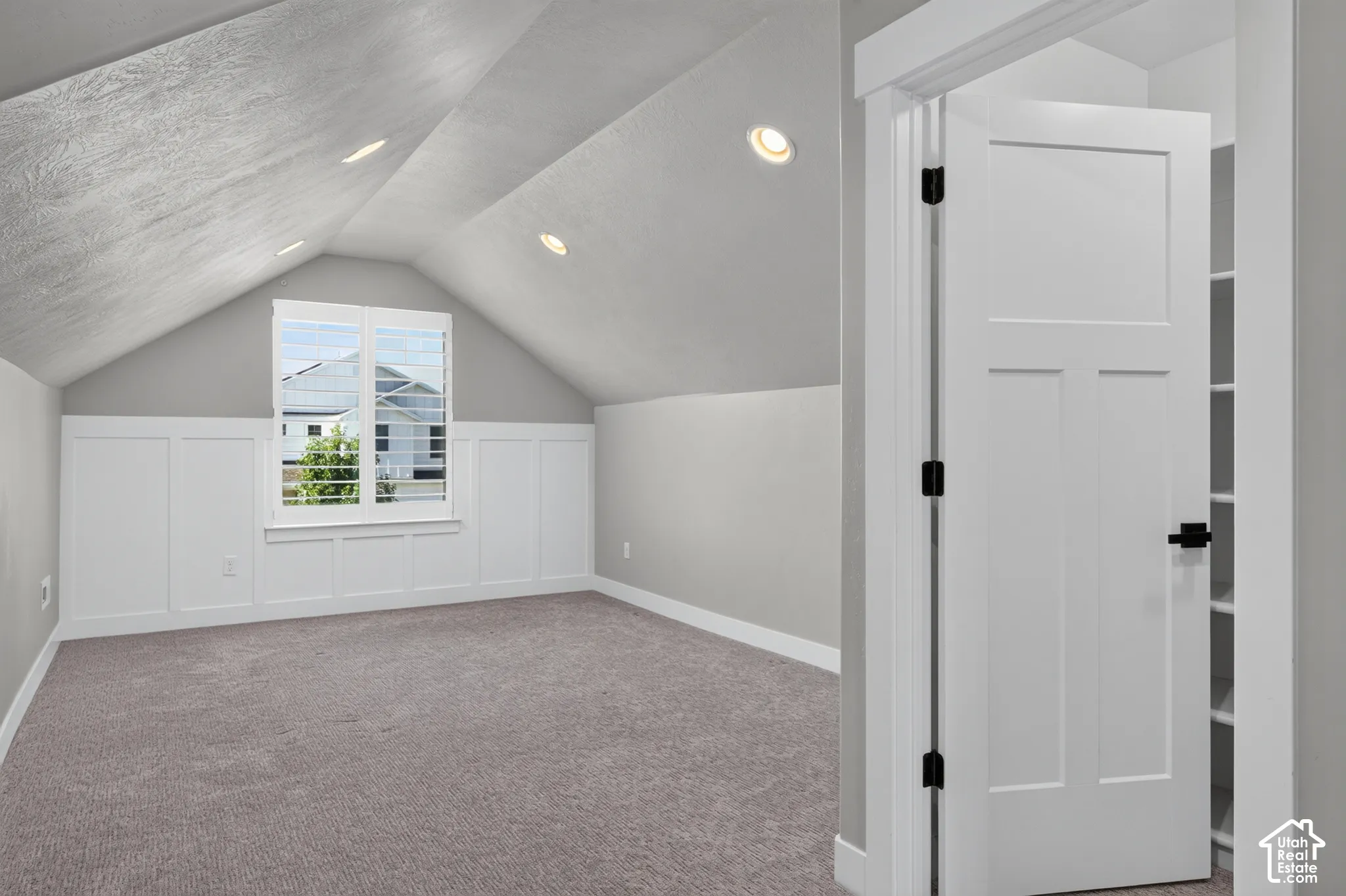 Room featuring an angled ceiling with recessed lighting, board and batten wall detailing, a window with louvered blinds, and gray carpeting