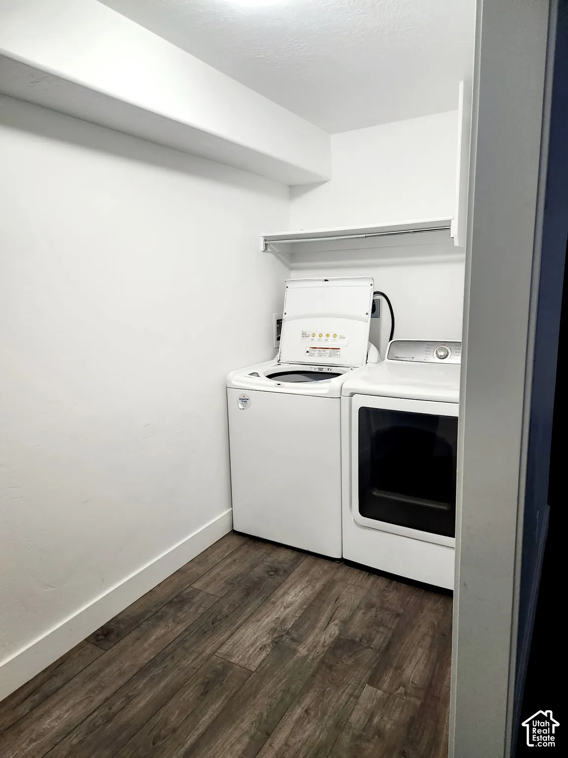 Dedicated laundry area featuring wood-finish flooring, white walls, and an overhead storage shelf