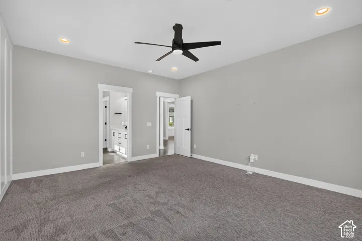 Spacious carpeted room featuring a ceiling fan, recessed lighting, and white trim molding