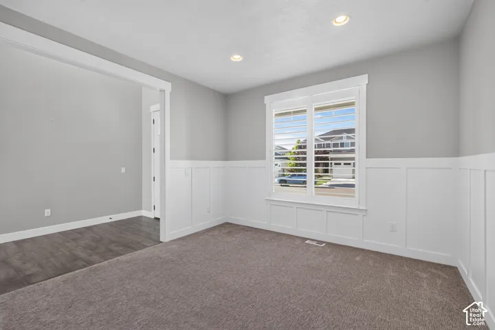 Bright interior space featuring a window with plantation shutters, recessed lighting, and wainscoting