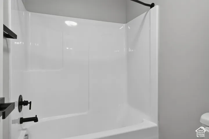 Bathtub and shower combination featuring a white surround, matte black fixtures, and a matte black shower curtain rod
