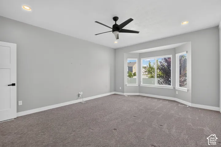 Spacious room featuring a bay window, recessed lighting, and a contemporary ceiling fan