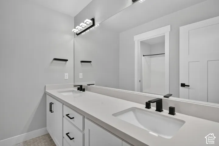 Spacious bathroom featuring a dual vanity with white cabinetry, light-toned countertops, and integrated rectangular sinks