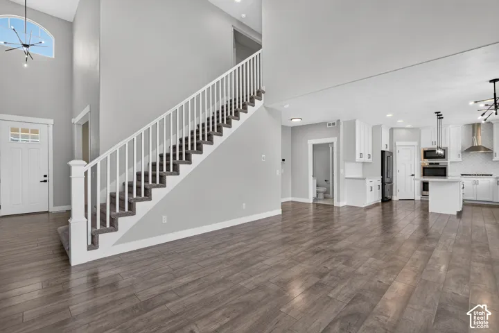 Open-concept living area featuring wood-finish flooring, a contemporary white kitchen with black appliances, a central island, and a built-in oven and microwave
