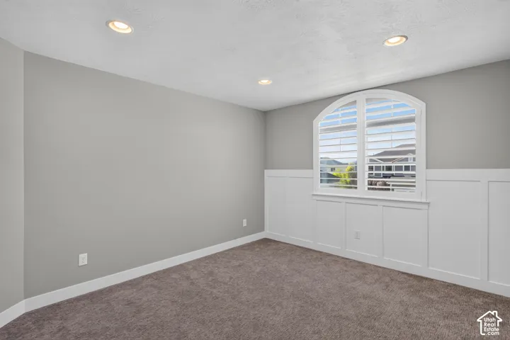 Room featuring an arched window with plantation shutters, recessed lighting, and board and batten wainscoting