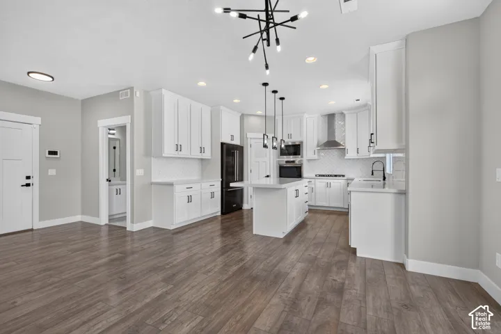 Contemporary open-concept kitchen featuring white cabinetry, an island with pendant lighting, stainless steel appliances, and wood-finish flooring
