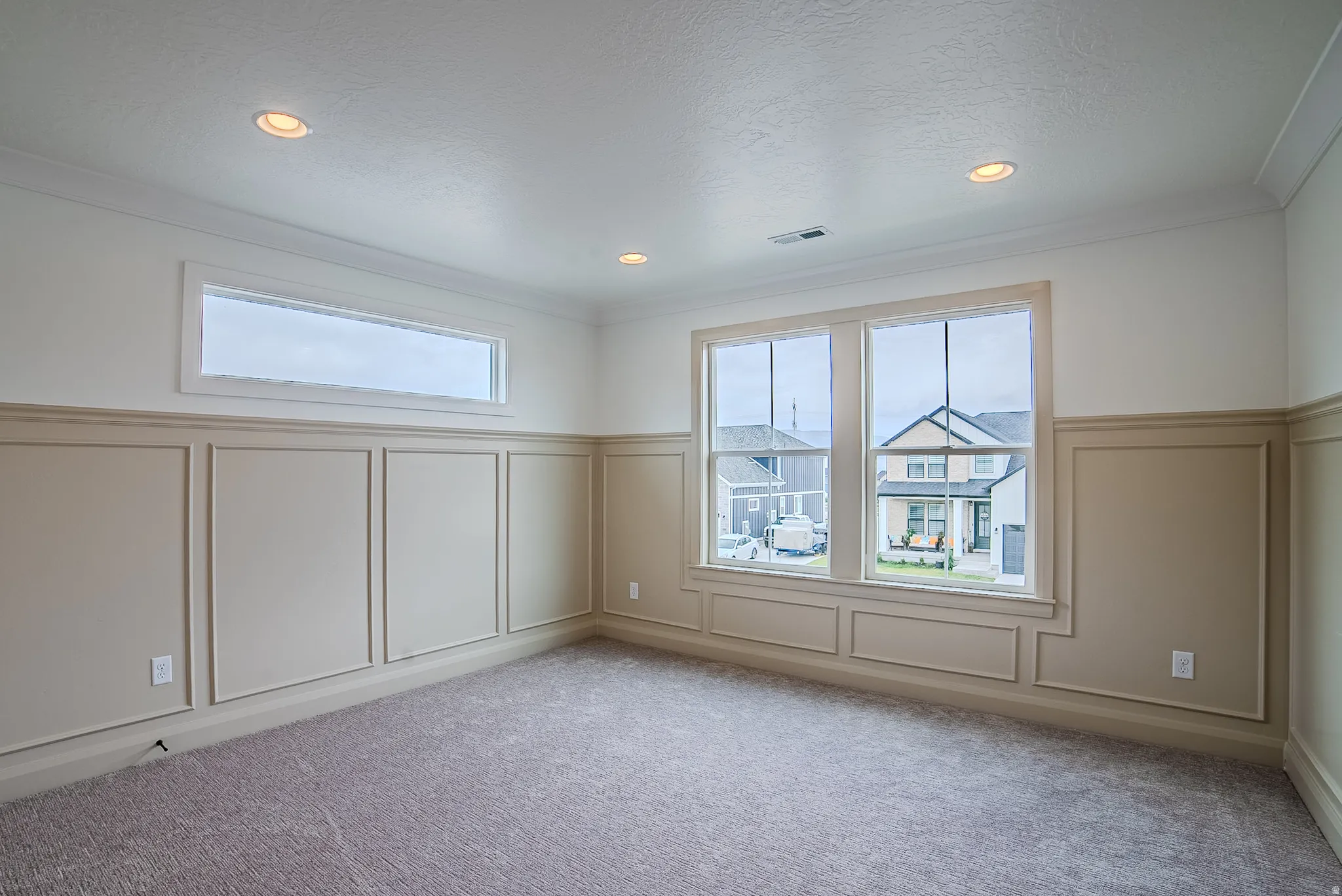 Interior room featuring wainscoting with decorative trim, multiple windows including a transom window, recessed lighting, and carpeted flooring