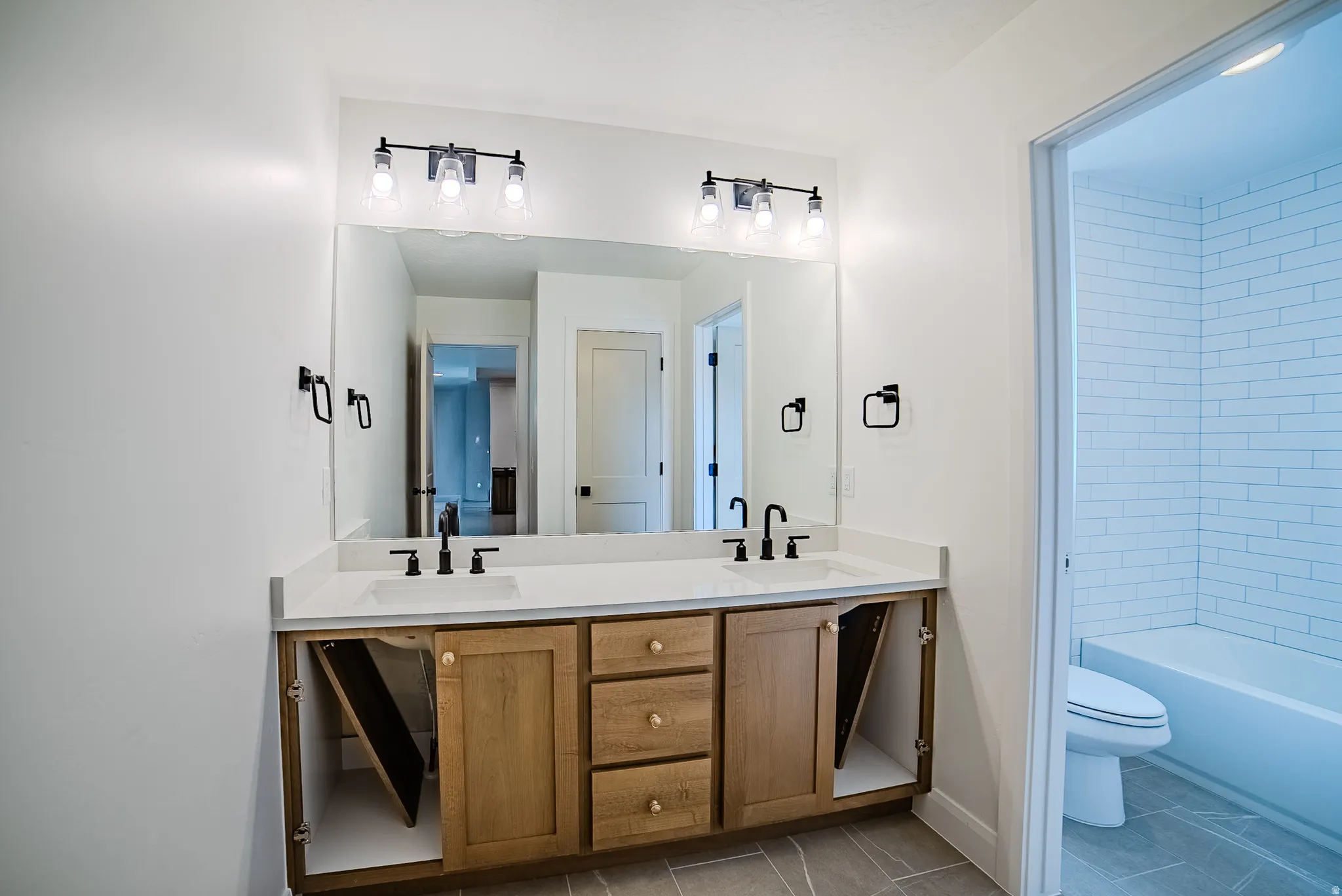 Double vanity featuring wood cabinetry, white countertops, and matte black fixtures