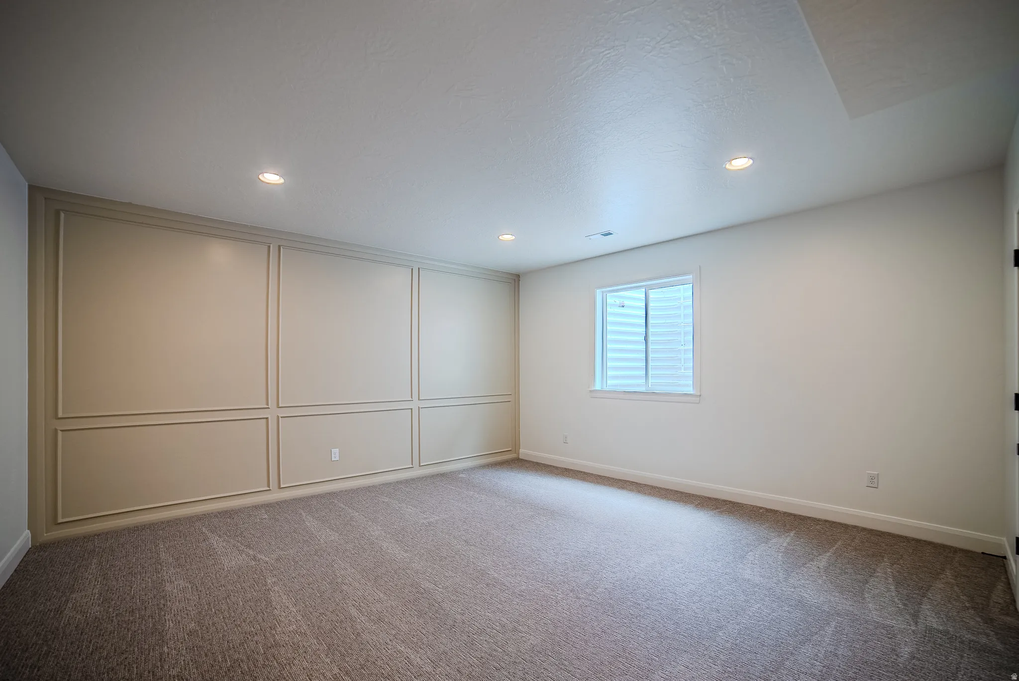 Accent wall featuring decorative panel molding and recessed lighting