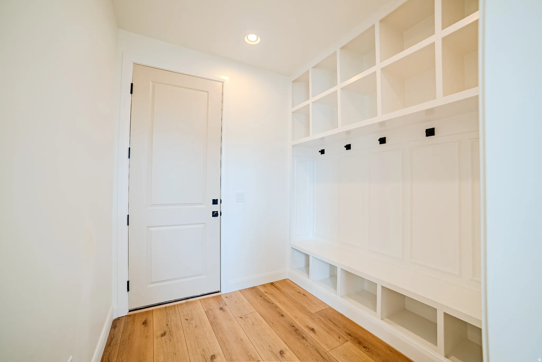 Entryway mudroom featuring built-in white cabinetry with storage cubbies, bench seating, and coat hooks