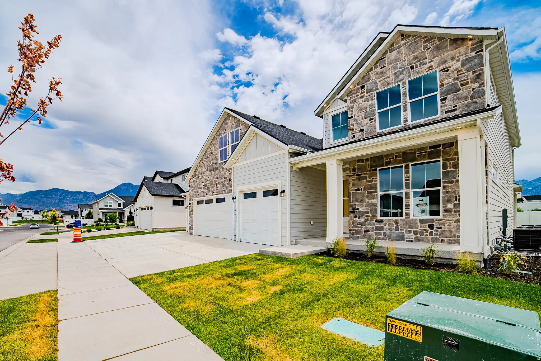 Contemporary stone and siding exterior featuring a covered porch with white columns, multiple large windows, and an attached two-car garage
