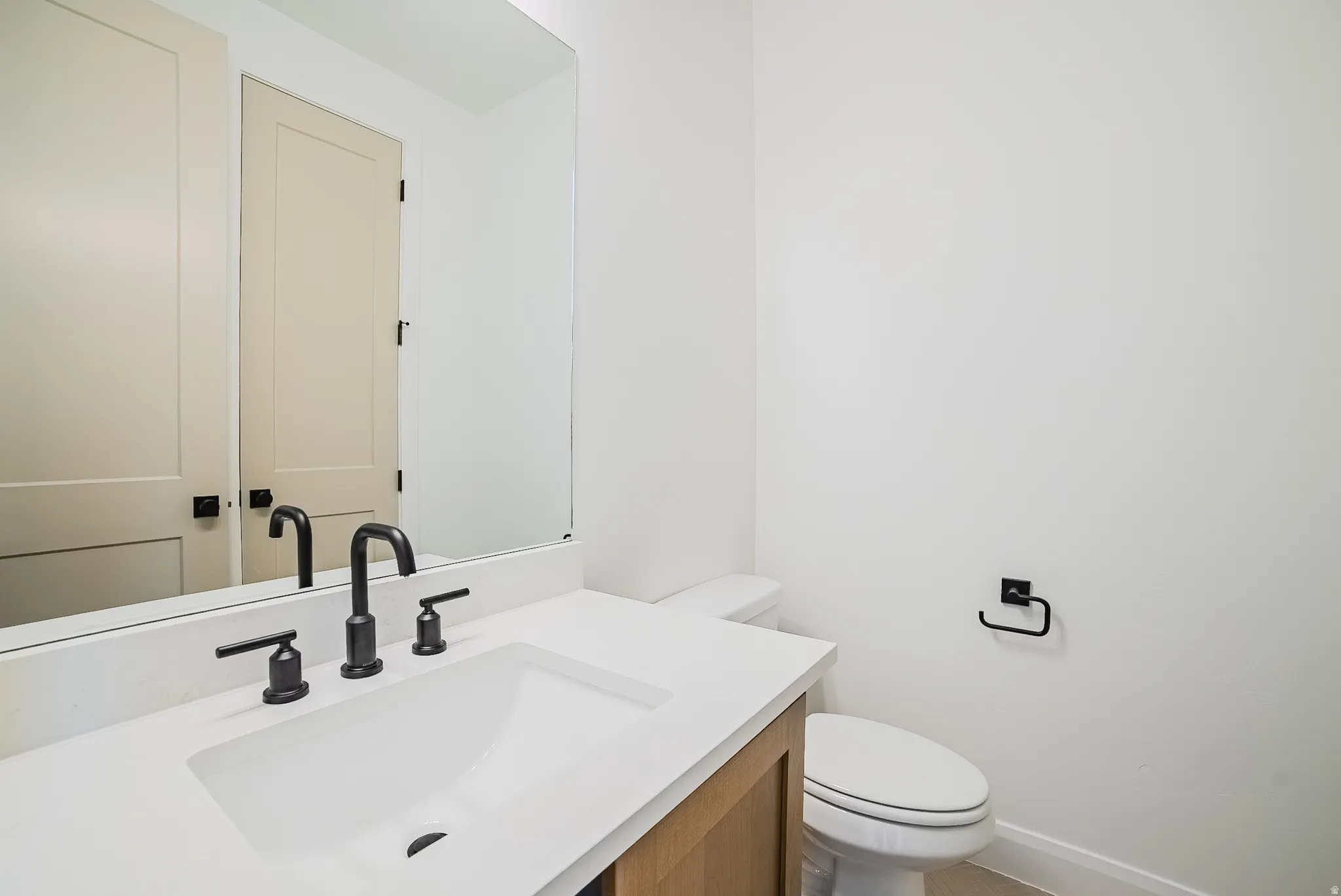 Modern bathroom featuring a wood-finish vanity, a rectangular integrated sink, and matte black fixtures