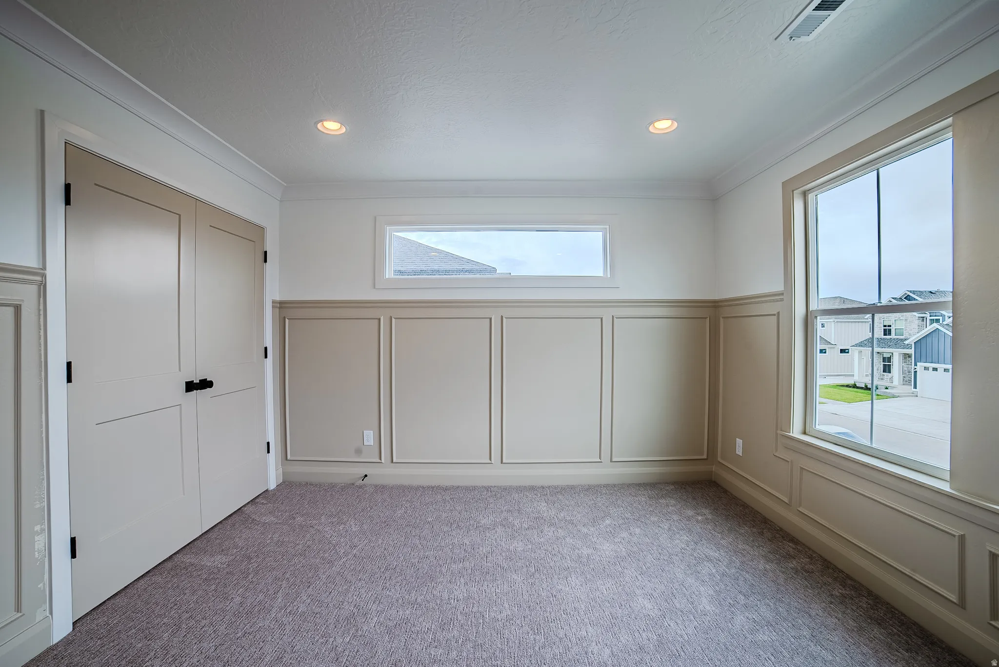Carpeted interior room featuring crown molding, recessed lighting, and wainscoting