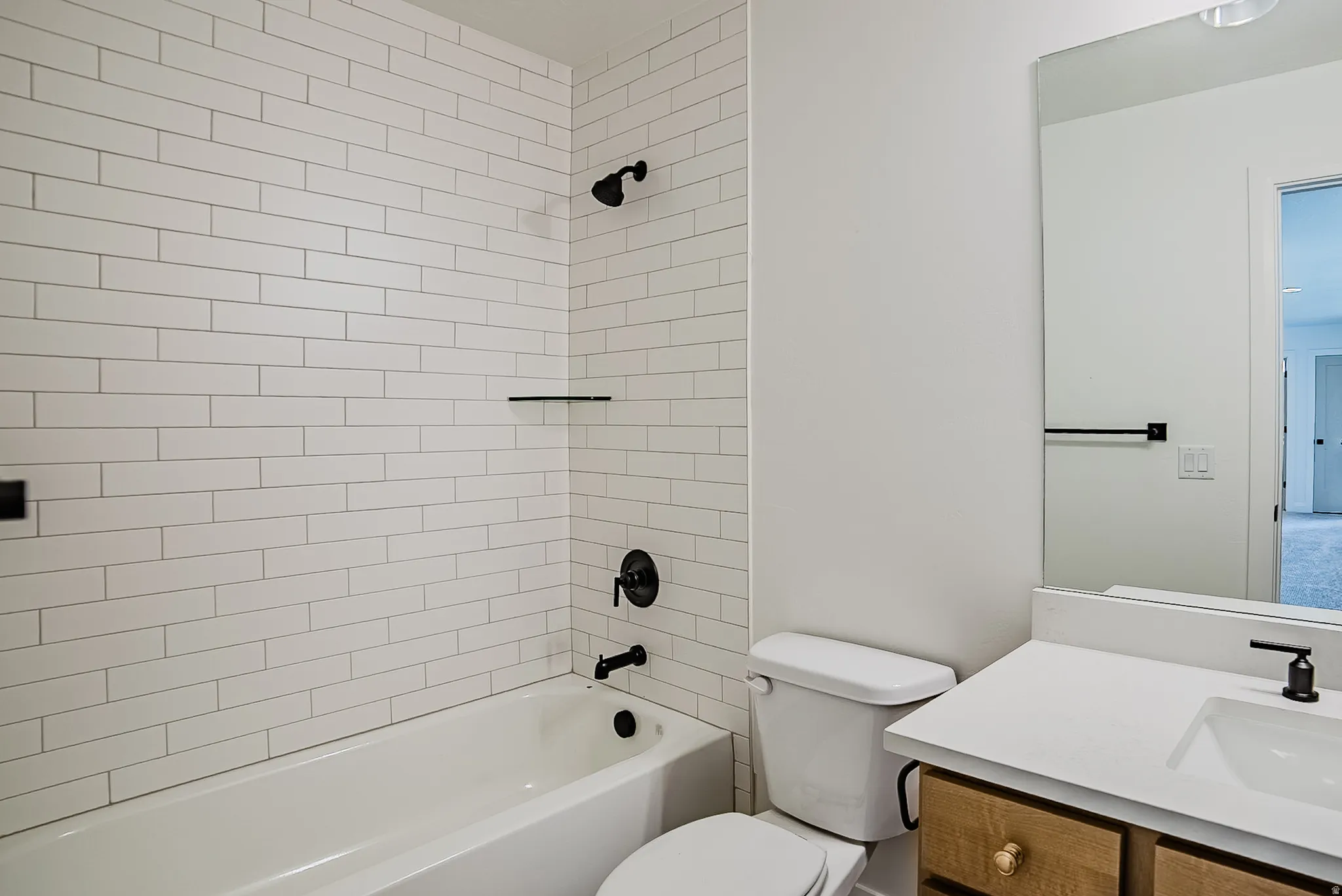 Bathroom featuring a white subway tile shower surround with matte black fixtures and a built-in shelf