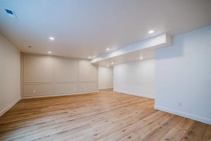 Spacious room featuring wood-finish flooring, recessed lighting, and decorative wall paneling