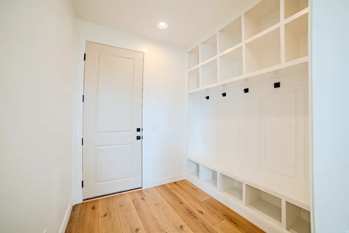 Entryway mudroom featuring built-in white cabinetry with storage cubbies, bench seating, and coat hooks