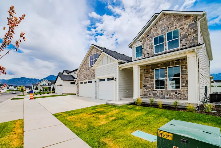Contemporary stone and siding exterior featuring a covered porch with white columns, multiple large windows, and an attached two-car garage
