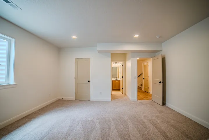 Spacious room featuring neutral carpet flooring, recessed lighting, and a white window with horizontal blinds
