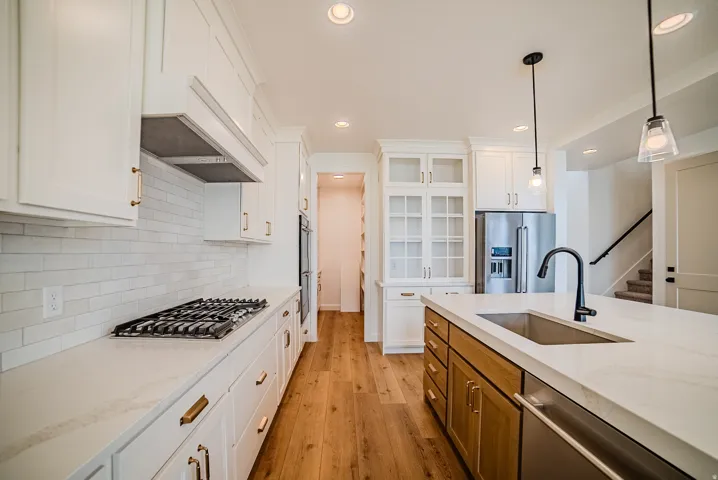 Contemporary kitchen featuring white cabinetry, a gas range with a tile backsplash, and a central island with a built-in sink