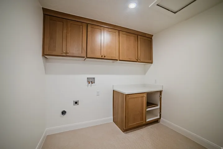 Dedicated utility space featuring ample wood-finish cabinetry, a white countertop, and recessed lighting