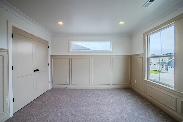 Carpeted interior room featuring crown molding, recessed lighting, and wainscoting