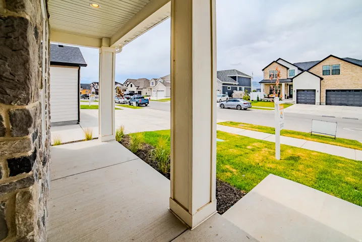 Covered porch featuring stone veneer siding and a concrete walkway