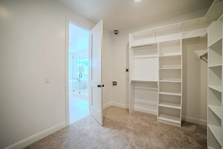 Walk-in closet featuring built-in shelving, dual hanging rods, and neutral-toned carpeting