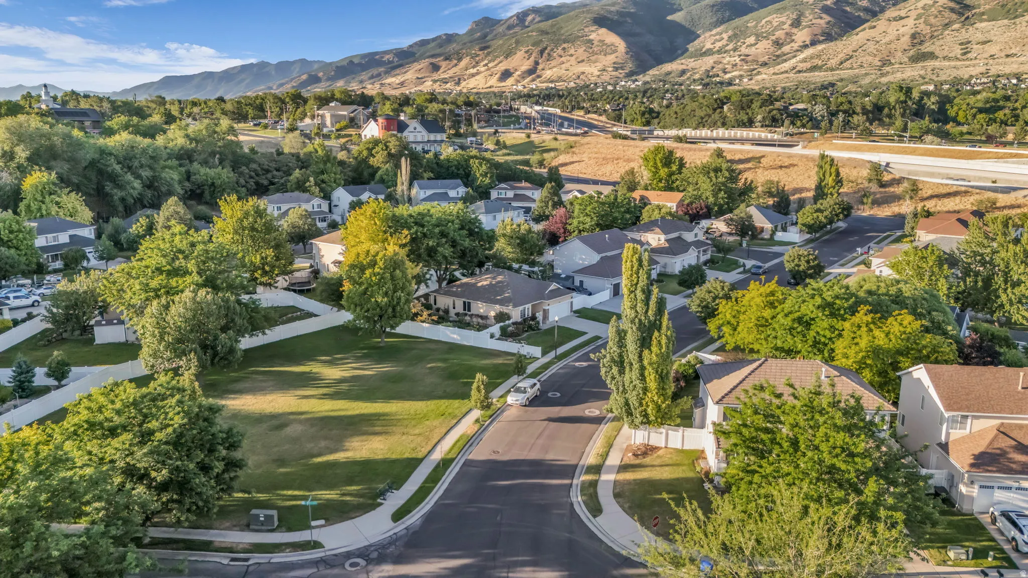Expansive residential lot featuring a manicured lawn and mature trees, surrounded by established homes