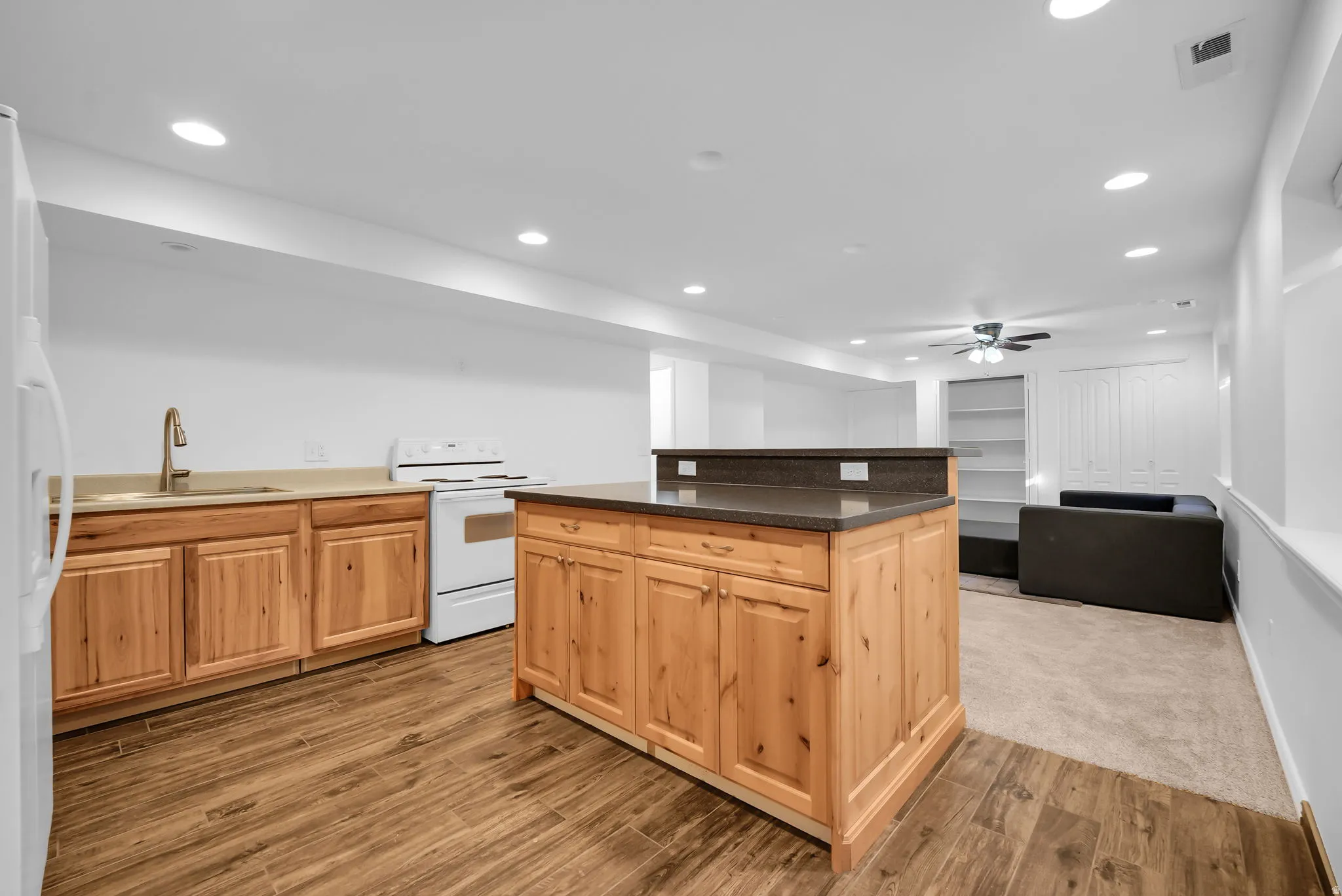 Open-concept living area featuring an island kitchen with wood-finish cabinetry and dark countertops