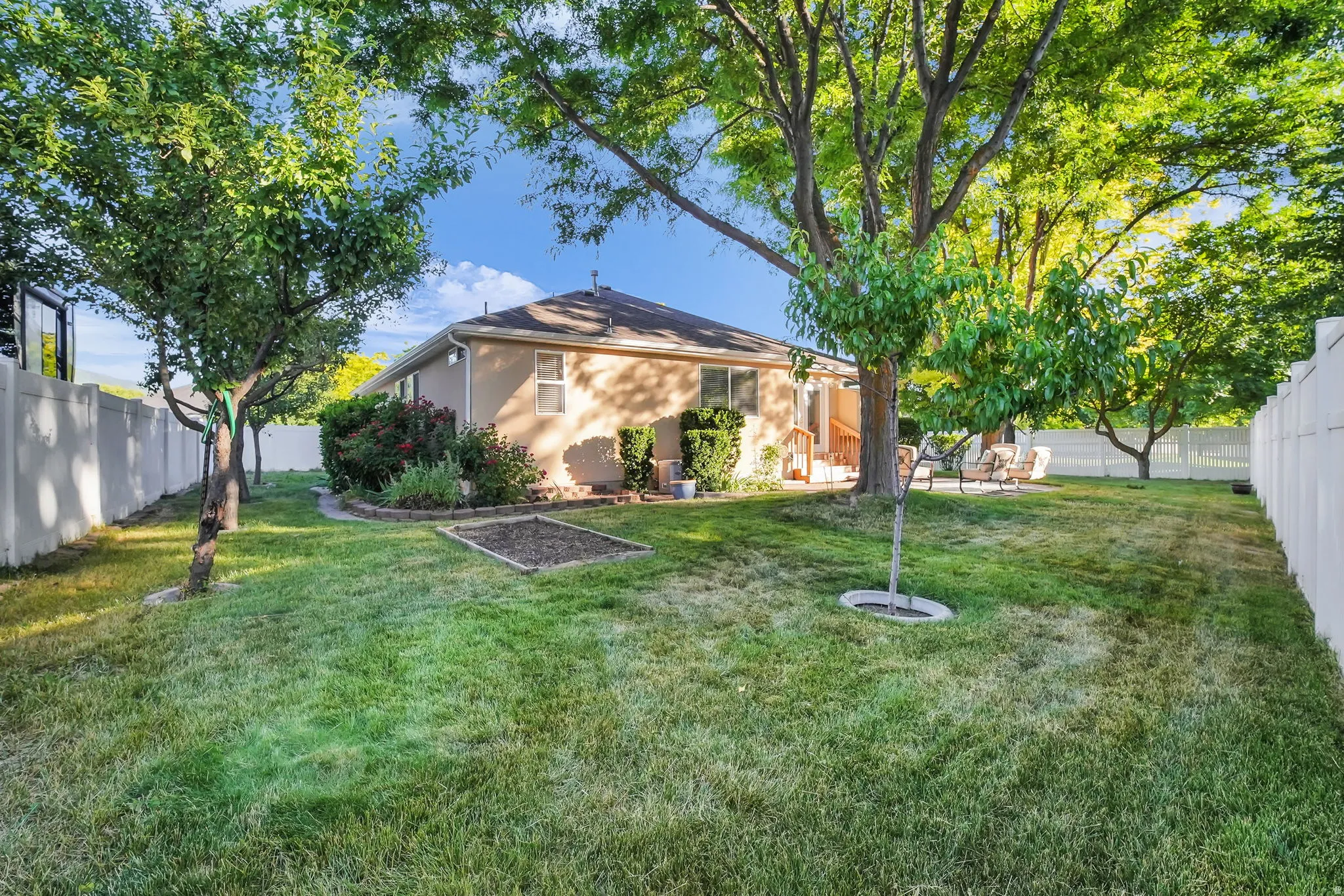 Expansive lawn area featuring mature trees and a vinyl privacy fence