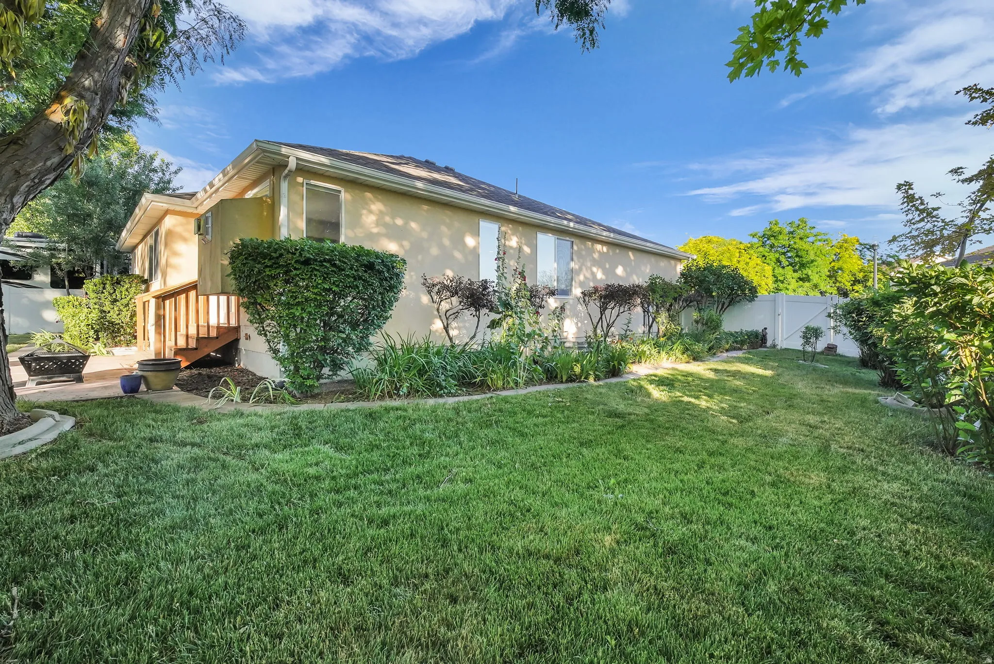 Expansive backyard featuring a manicured lawn, established landscaping, and a multi-level wood deck
