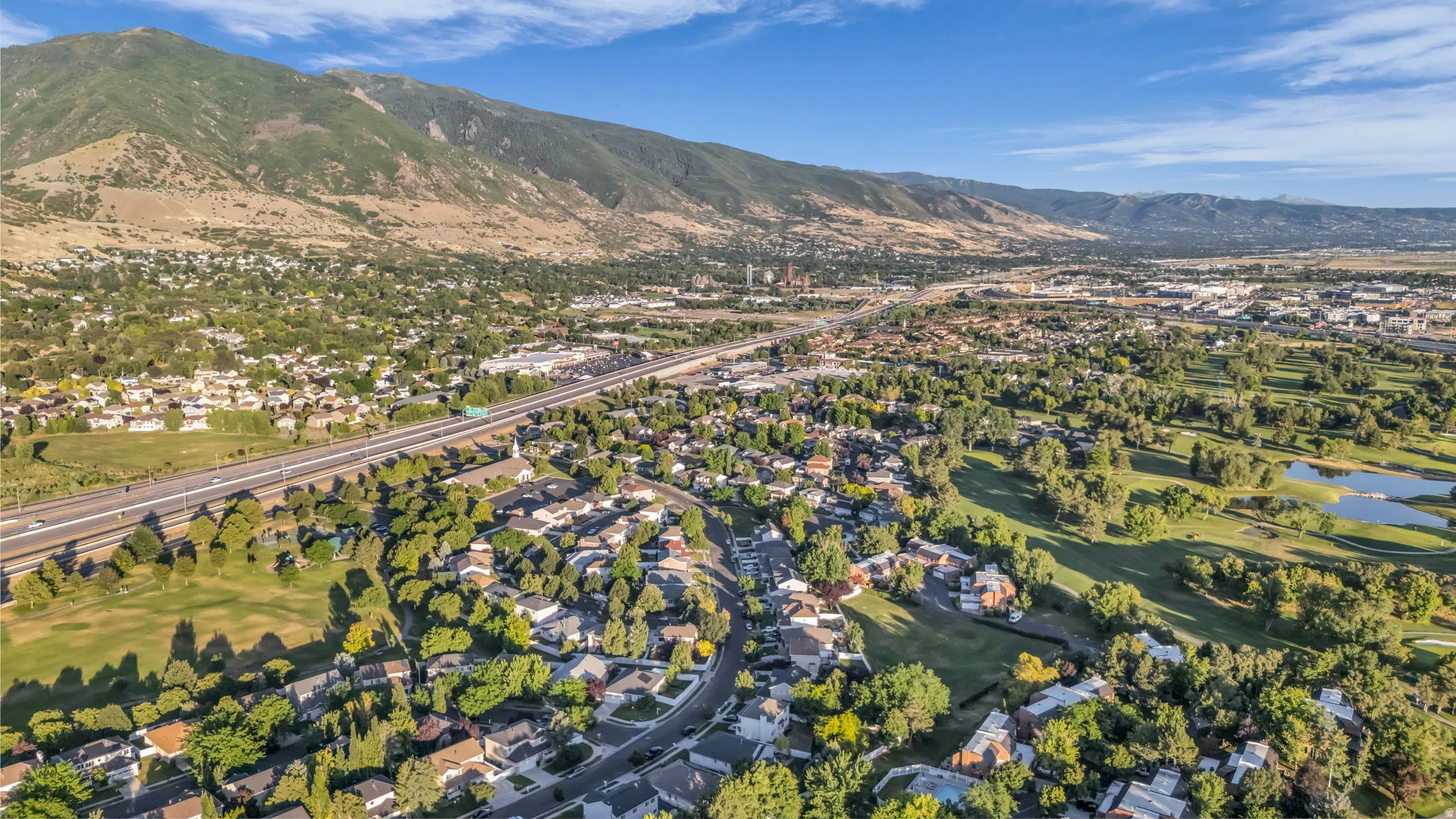 Expansive aerial landscape featuring a residential community, a highway, and a golf course with water features