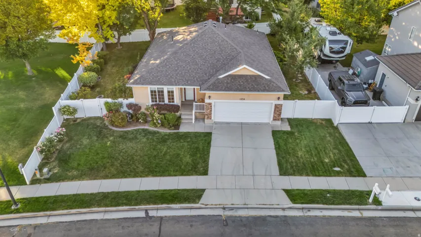 Single-story residence featuring a two-car garage, concrete driveway, and a white vinyl fence
