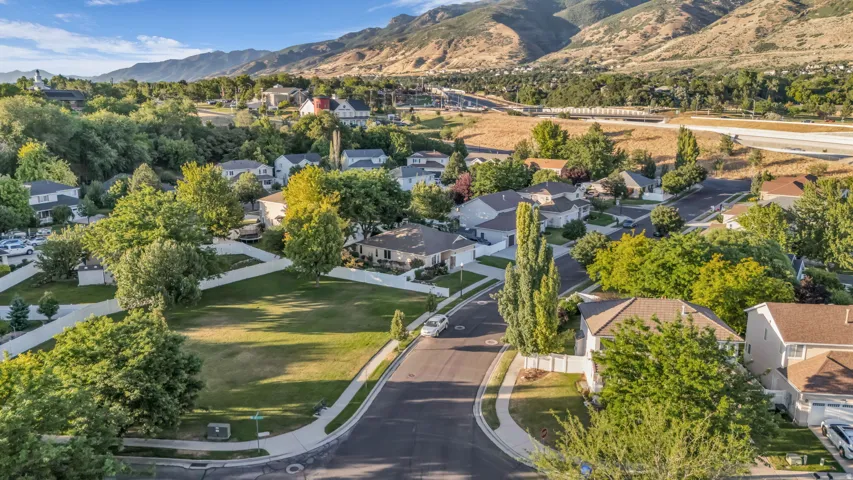 Expansive residential lot featuring a manicured lawn and mature trees, surrounded by established homes