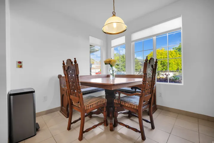 Dining area featuring a central chandelier, multiple large windows with grid patterns, and tile flooring