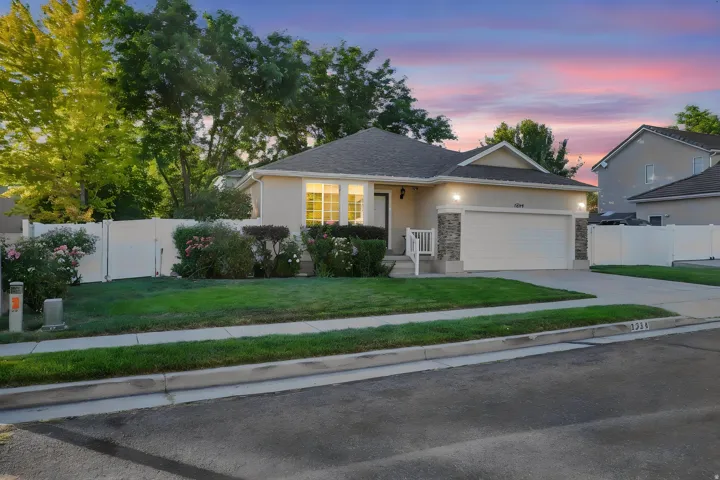Stucco and stone facade with an attached two-car garage, concrete driveway, and front yard landscaping