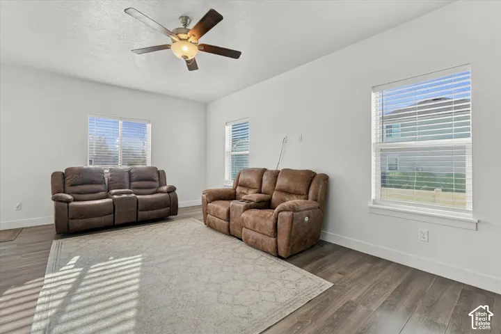 Wood-finish flooring, white walls, and a ceiling fan with integrated lighting
