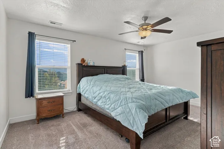 Primary bedroom with natural light and ceiling fan.  Lovely views.