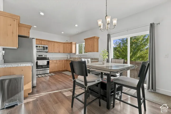 Kitchen and dining area featuring wood-finish flooring, light wood cabinetry, stainless steel appliances, and a sliding glass door