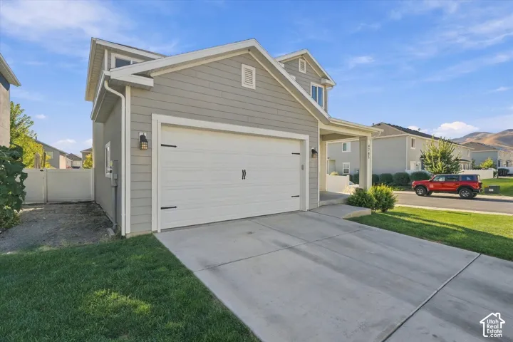 Two-story residence with light gray siding, white garage door with dark hardware, and a paved driveway