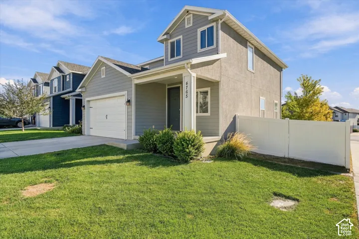 Two-story residence featuring a covered entry, attached garage, and a privacy fence