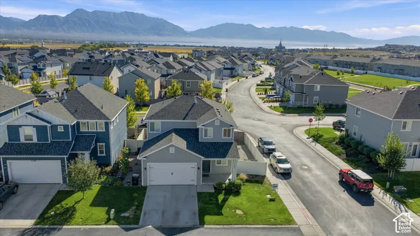 Residential street with single-family homes, mature landscaping, and mountain backdrops