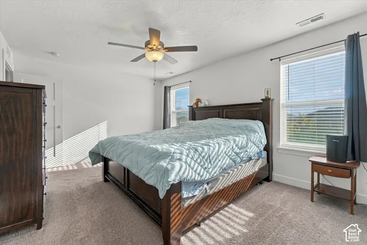 Primary bedroom with natural light and ceiling fan.  Lovely views.
