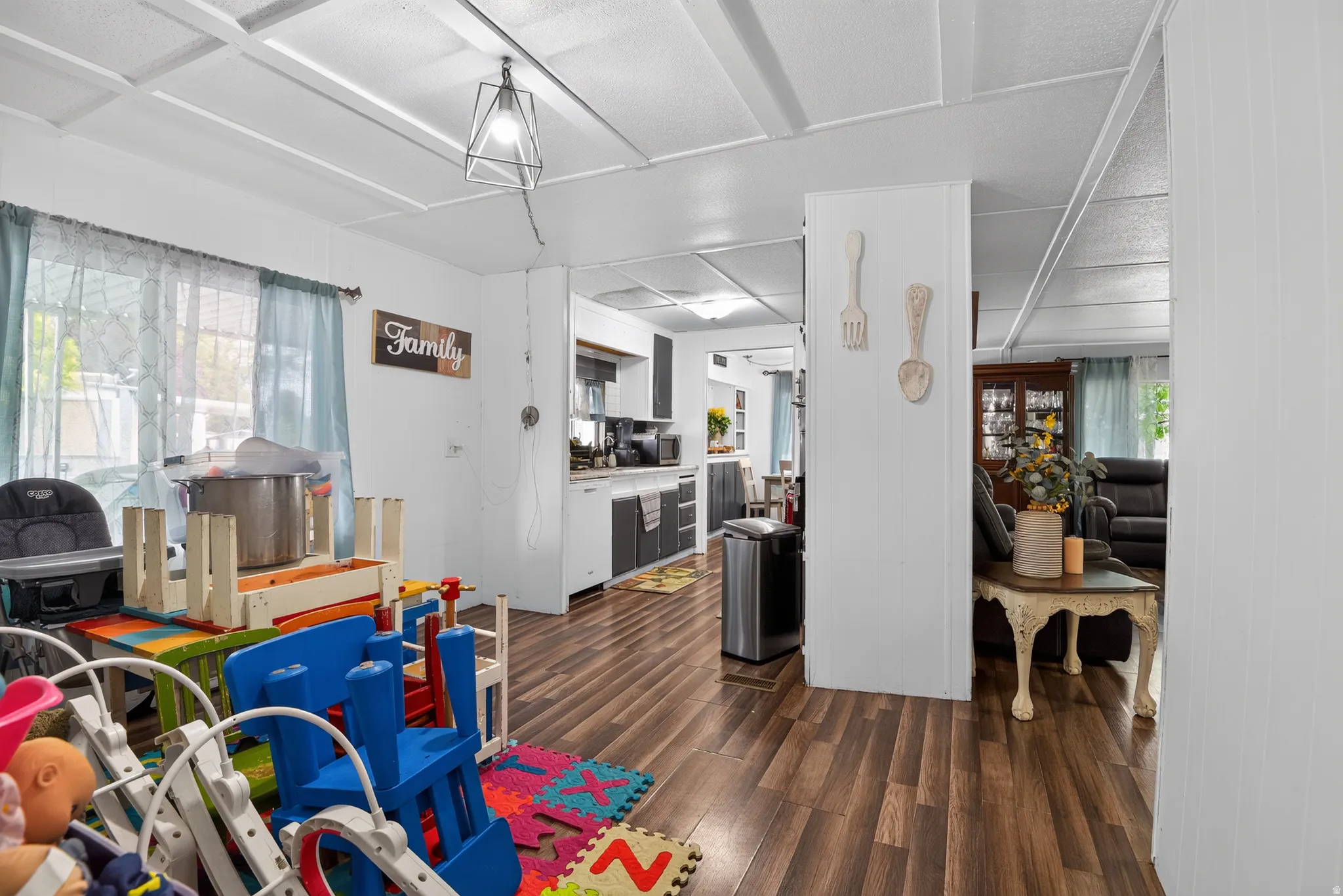 Open-concept interior featuring wood-finish flooring, white paneling, and a geometric pendant light fixture