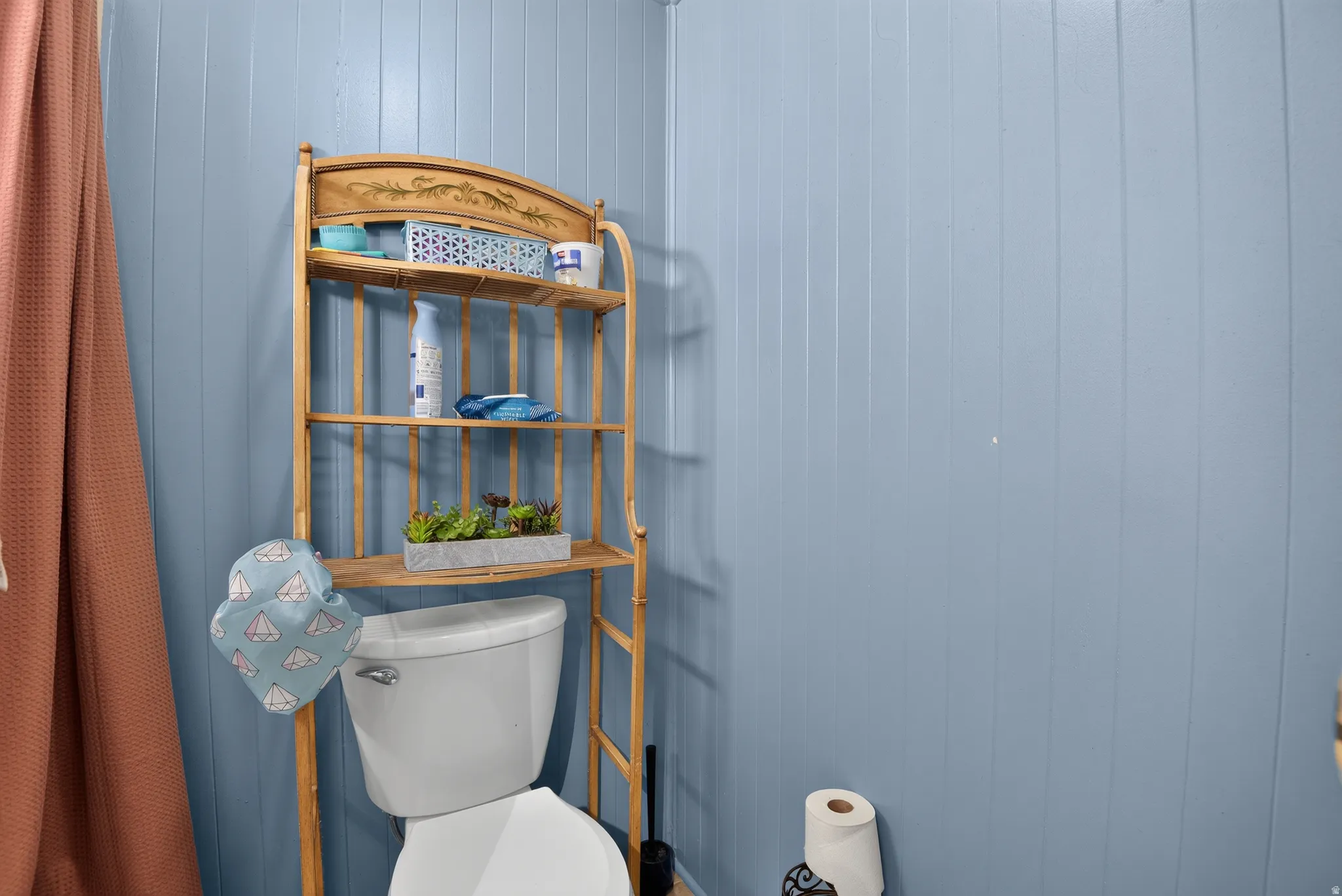 Bathroom featuring blue vertical paneling and a white toilet