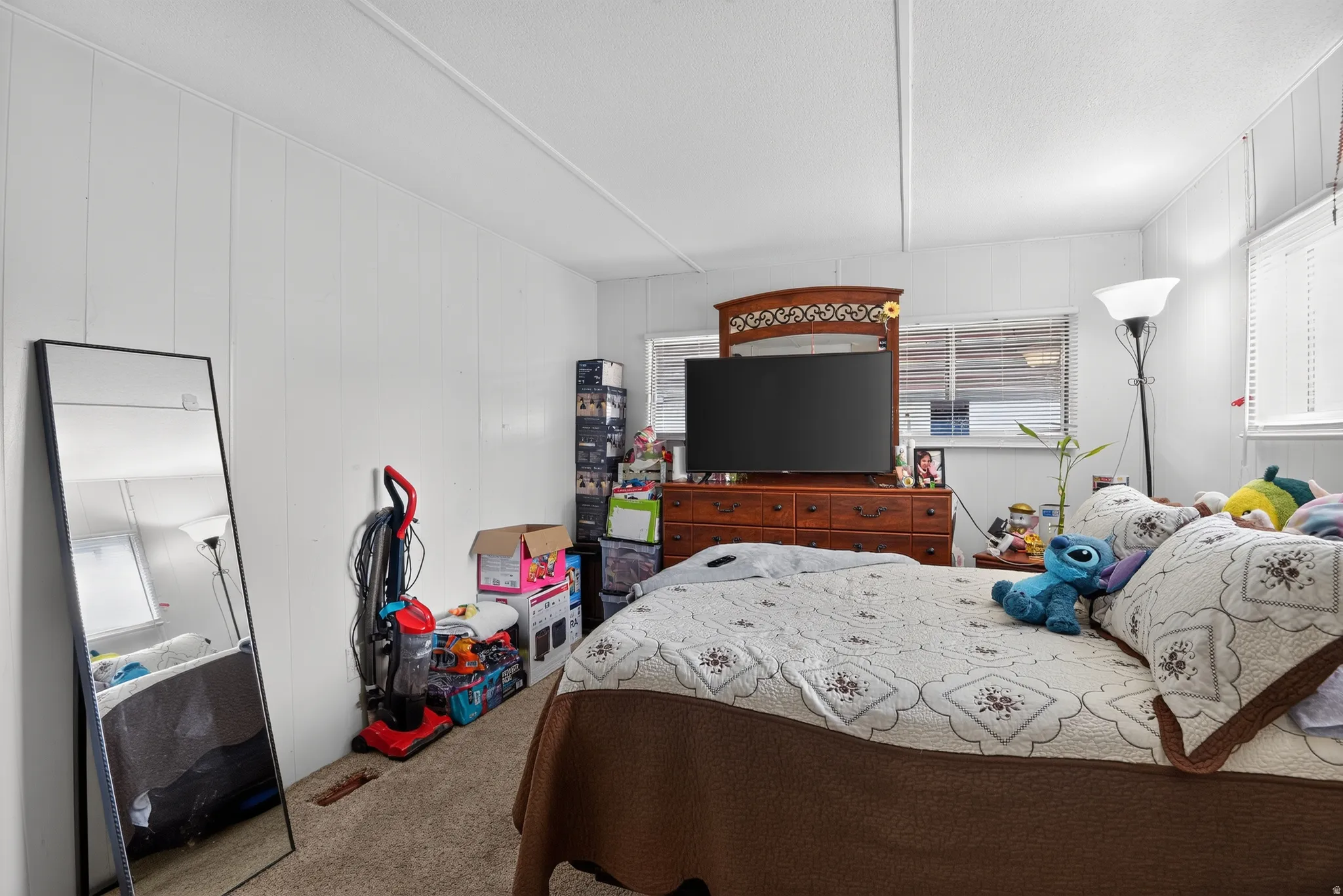 Bedroom featuring white paneled walls, carpet flooring, and white window blinds